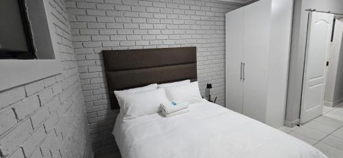 a bedroom with a white bed with a brick wall at Grace Villas 35 in East London