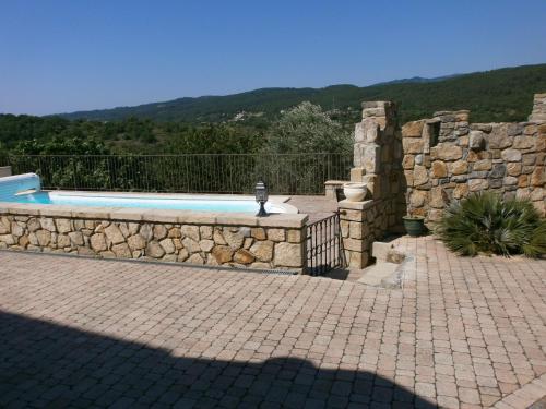 une piscine avec un mur en pierre à côté d'une clôture en pierre dans l'établissement LE GRAND CHENE, à Saint-Étienne-de-Fontbellon
