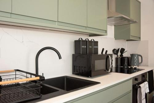 a kitchen counter with a sink and a microwave at Cosy 2-Bed Apartment in Penarth Town Flat 1 in Cardiff