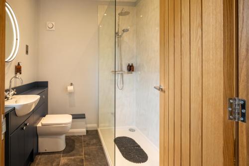 a bathroom with a shower and a toilet and a sink at The Coach House Suffolk in Lowestoft