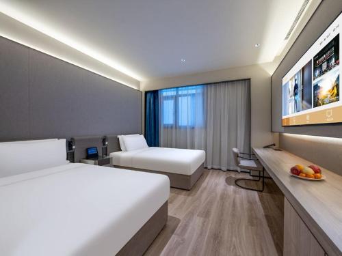 a hotel room with two beds and a desk with a fruit bowl at Tianjin Binjiang Road Pedestrian Street Orange Crystal Hotel in Tianjin