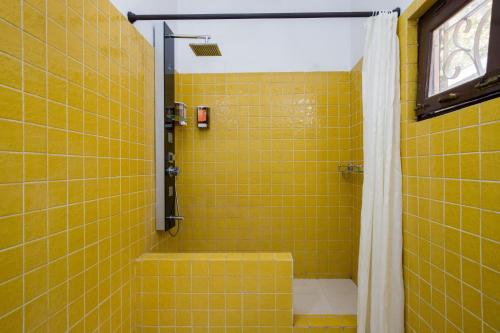 ein gelb gefliestes Badezimmer mit Dusche und Badewanne in der Unterkunft Heaven on Hills by The StayCationer in Bhīm Tāl