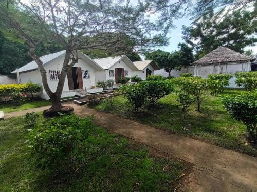 a white house with a tree in the yard at Hôtel-bungalows La Pirogue in Sambava