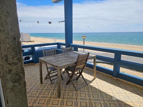 a wooden table and chairs on a balcony overlooking the beach at Blife Vistaya private rooms at Faro beach in Faro