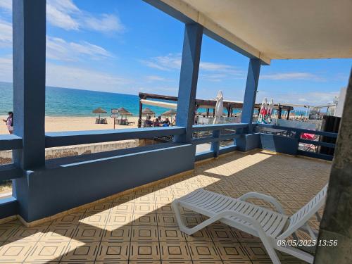a white bench sitting on a balcony overlooking the beach at Blife Vistaya private rooms at Faro beach in Faro