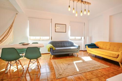 a living room with a couch and a table and chairs at Charming T3 with patio, beach and surf in Peniche