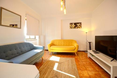 a living room with a couch and a television at Charming T3 with patio, beach and surf in Peniche