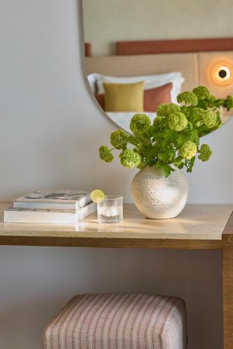 a plant in a vase on a table with a mirror at Boutique 5 Hotel & Spa - Adults Only in Kiotari