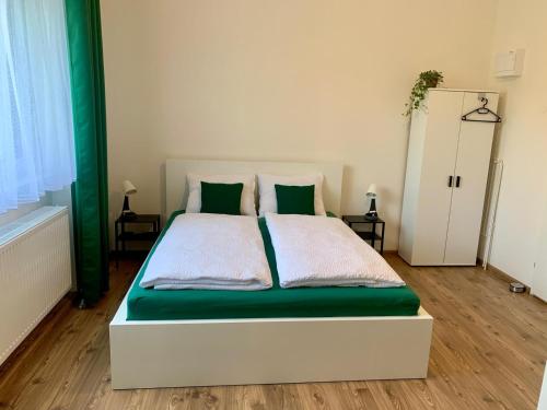 a bedroom with a bed with green and white sheets at Apartmány 150 in Uherský Ostroh
