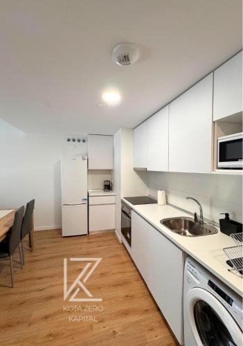 a kitchen with white cabinets and a sink and a table at KOTA Zero Rivas Center 478 in Rivas-Vaciamadrid