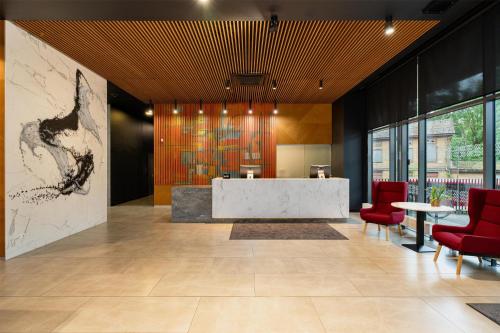 a lobby with a reception desk and red chairs at Park Inn by Radisson Riga Valdemara in Rīga