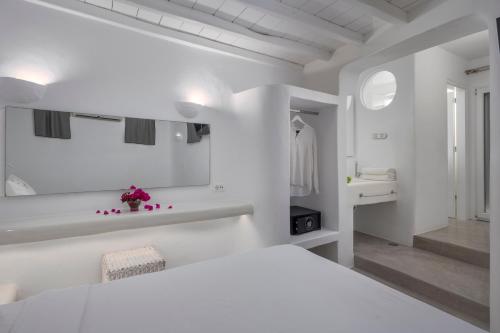 a white bedroom with a bed and a bathroom at Flaskos Luxury Suites in Agios Stefanos