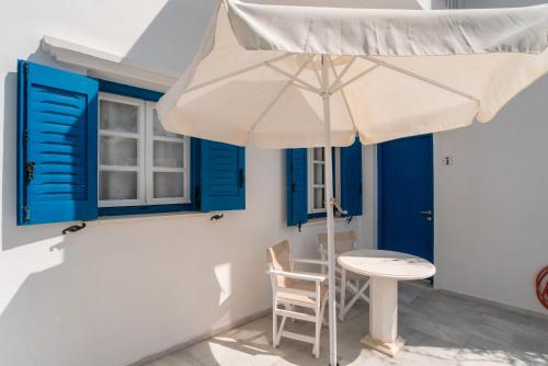 a table and an umbrella in a room with blue windows at Maroulis Studios Naxos in Mikri Vigla