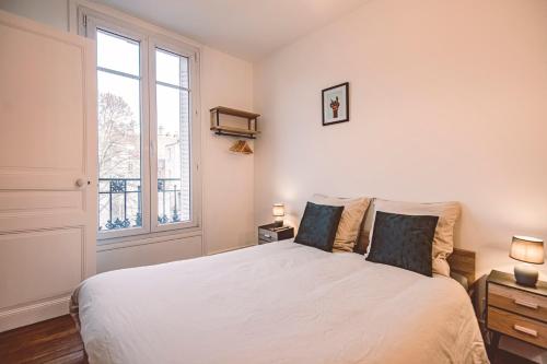 une chambre avec un grand lit blanc avec une fenêtre dans l'établissement Charme de l'ancien pour cet appartement entièrement rénové rue jeanne d'arc, à Reims