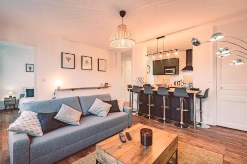 un salon avec un canapé et une cuisine dans l'établissement Charme de l'ancien pour cet appartement entièrement rénové rue jeanne d'arc, à Reims