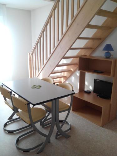 a table and chairs in a room with a staircase at Sphinx Résidences - Tempologis Mémorial in Caen
