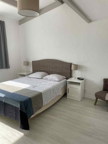 une chambre blanche avec un lit et une chaise dans l'établissement Belle maison quartier calme proche plage mer, à Saint-Hilaire-de-Riez