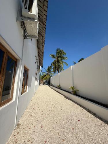 an empty hallway of a white building with palm trees at Zanzibar Huria in Bwejuu