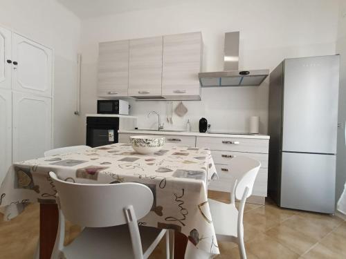 a kitchen with a table and chairs and a refrigerator at Marinella House in Siracusa