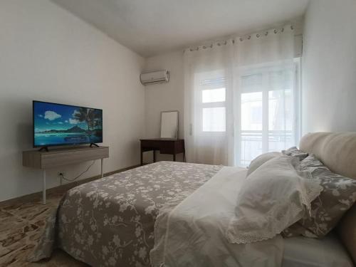 a bedroom with a bed and a flat screen tv at Marinella House in Siracusa