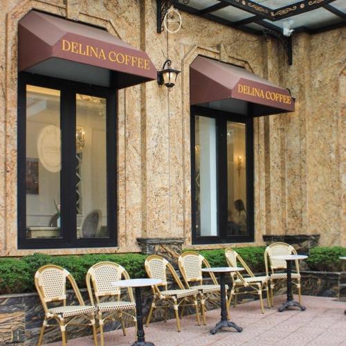 a group of chairs and tables in front of a building at Delina Castle Coffee & Hotel in Hanoi