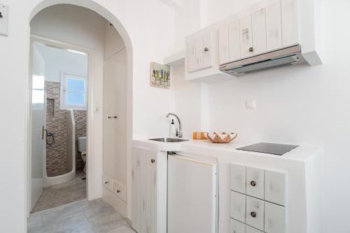 a kitchen with white cabinets and a sink at Maroulis Studios Naxos in Mikri Vigla
