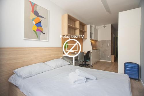 a bedroom with a white bed and a desk at Apartamenty Collegia in Gdańsk