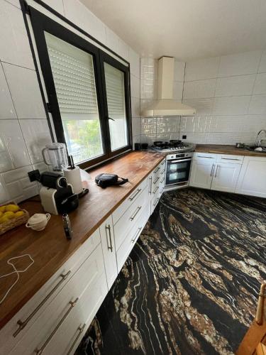 a kitchen with white cabinets and wooden counter tops at House Garden near Paris Roissy Calm zone in Les Pavillons-sous-Bois