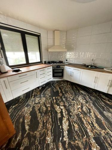 une cuisine avec des placards blancs et un grand tapis dans l'établissement House Garden near Paris Roissy Calm zone, à Les Pavillons-sous-Bois