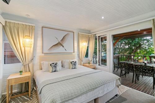 a bedroom with a bed and a balcony with a table at Knysna River Club Getaways - Luxury waterfront chalets in Knysna