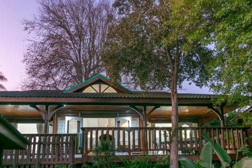 a large house with a porch and a tree at Knysna River Club Getaways - Luxury waterfront chalets in Knysna
