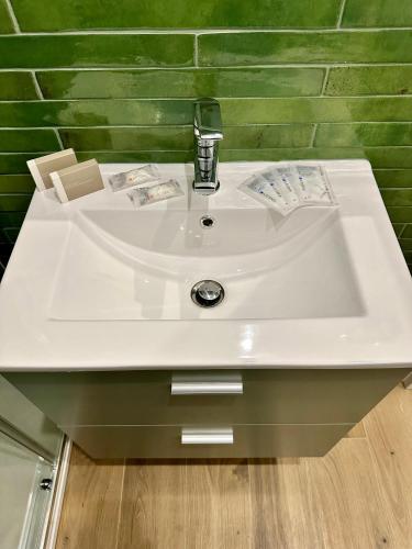 a white sink in a bathroom with a green wall at Casa San Clemente - Porta Susa FS in Turin