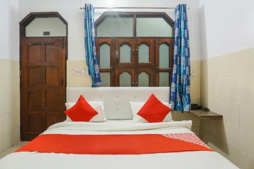 a bedroom with a bed with red and white pillows at Hotel O Gold Stayz in Ballabgarh