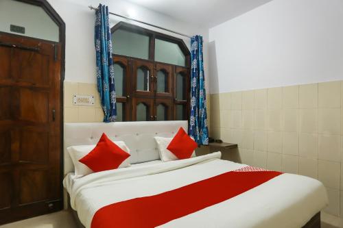 a bedroom with a large bed with red pillows at Hotel O Gold Stayz in Ballabgarh