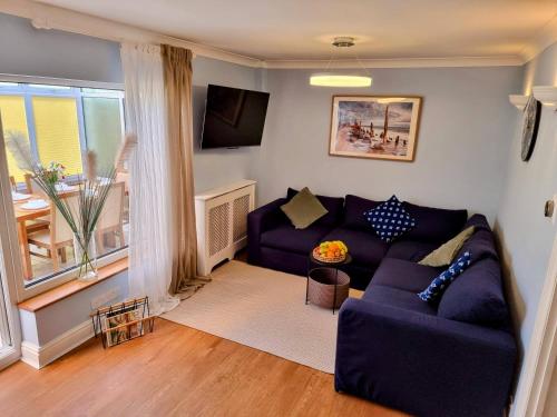 a living room with a purple couch and a window at 28 ExcellentStays - Heathrow - 5 Bedroom House in Stanwell