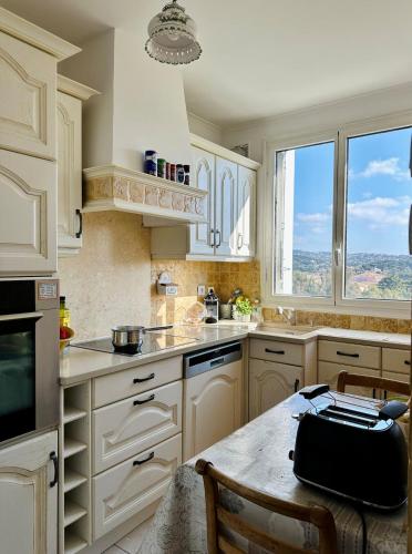une cuisine avec des armoires blanches et une table avec un sac dessus dans l'établissement Le Belvedere Golf -Ste Maxime, à Sainte-Maxime