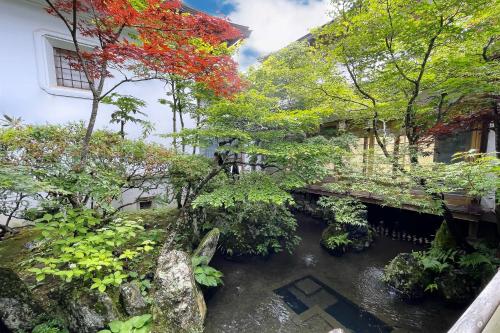 a garden with trees and a river in front of a building at 高野山 宿坊 総持院 -Koyasan Shukubo Sojiin- in Koyasan