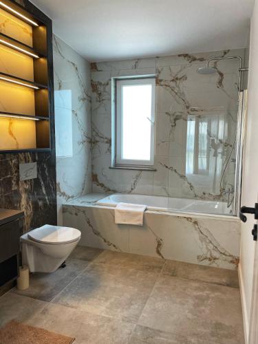 a bathroom with a tub and a toilet and a sink at Emerald Home in Suceava