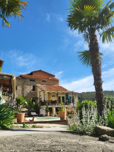 a house with a palm tree in front of it at Chambres d'hôtes La Storya in Meyras