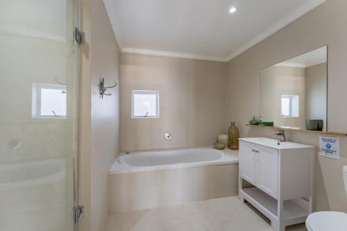 a white bathroom with a tub and a sink at 9 Quarter Deck in St Francis Bay
