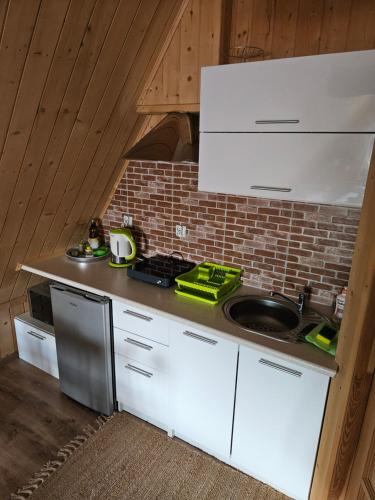 a kitchen with white cabinets and a brick wall at Pokoje gościnne Zosia in Kościelisko