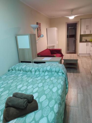 a bedroom with a green bed and a kitchen at La Merced B in Cádiz