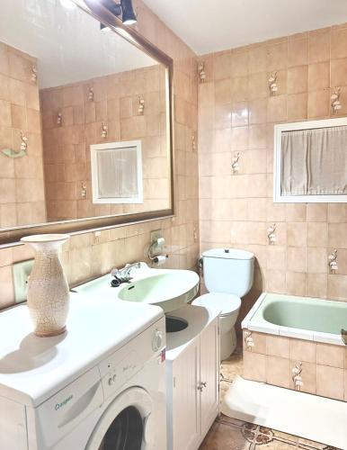 a bathroom with a sink and a washing machine at Chalets con piscinas privadas junto al mar in Cala en Bosc
