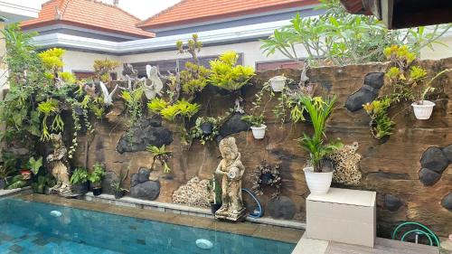 a wall with plants and a statue next to a pool at Darmanata Villa 2 in Ubud