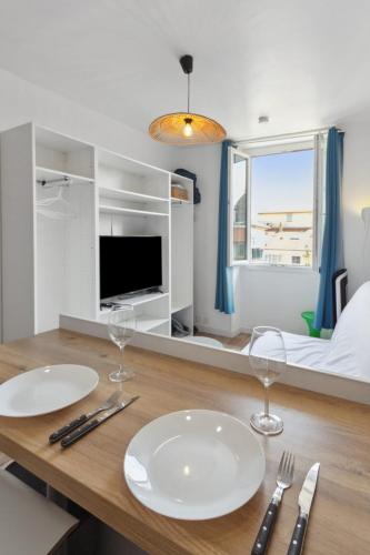 - une table à manger avec 2 assiettes blanches et des verres à vin dans l'établissement L'Opéra - Hypercentre - Cosy - No elevator - Minimalist - Sea, à Nice