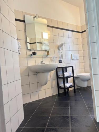 a bathroom with a sink and a toilet and a mirror at Albavillage Hotel Wellness & Camping in Alba