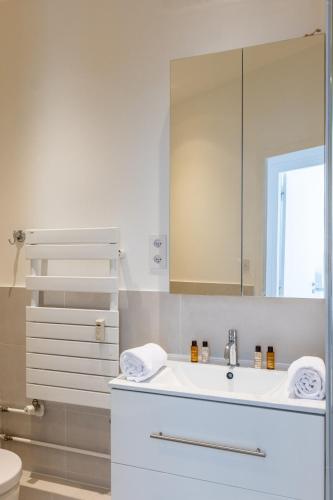 une salle de bain blanche avec un lavabo et un miroir dans l'établissement Veeve - Ethereal Light, à Paris