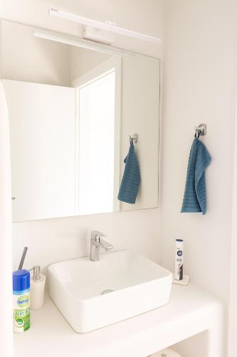a bathroom with a white sink and a mirror at Seafront Alos Gem - Loutra Seaview Escape in Loutra