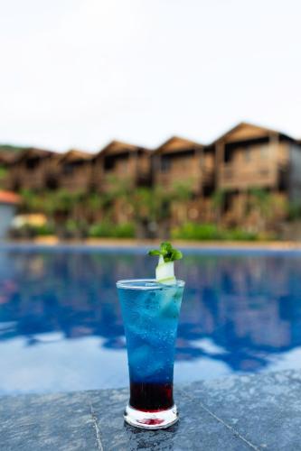 a drink sitting on a table next to a pool at Axiom Resorts Luxury Cottages, Arambol in Arambol