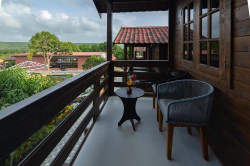 a balcony with two chairs and a table on it at Axiom Resorts Luxury Cottages, Arambol in Arambol